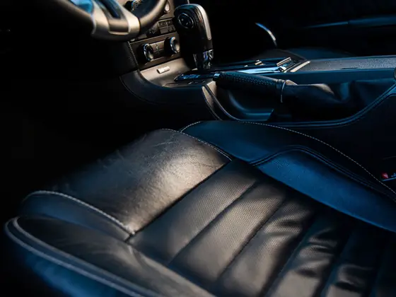 Close view of leather car seating showing stitching and bolster wear