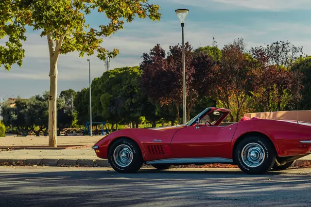 A red Chevrolet Corvette Stingray convertible parked on a tree-lined road